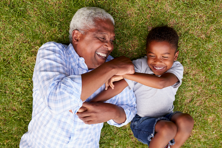 Grandfather and grandson play lying on grass, aerial view