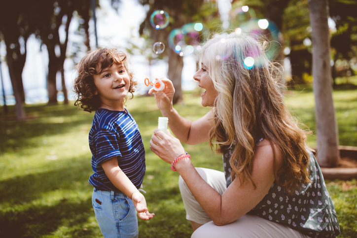 Grandma and grandson laughing and blowing bubbles at the park