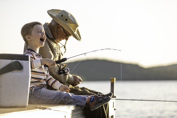 Grandfather and Grandson Fishing At Sunset in Summer